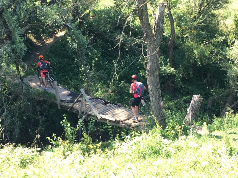 Meșendorf. Traversing different terrains. Pushing bikes across a raggety-looking bridge.